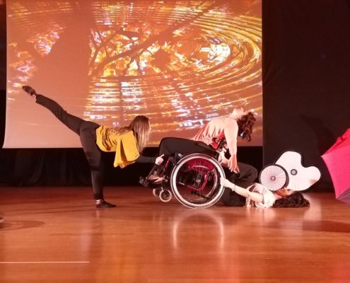 Giovanna Barbero e due sue allieve, di cui quella centrale con disabilità motoria, si esibiscono in una performance di danza.